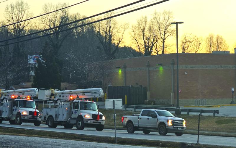 Enoch Autry/The Clayton Tribune. As dawn sets on Tuesday evening, power company crews are still working hard into the night.