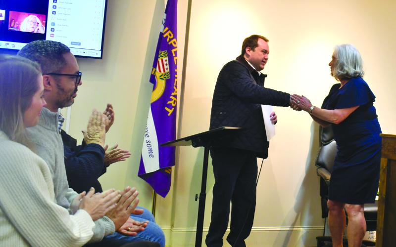 Megan Horn/The Clayton Tribune. Tuesday meeting attendees in Sky Valley clap as new council member CareySue Beasley shakes hands with City Attorney Douglas Kidd after taking the Oath of Office.