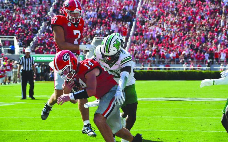 Wesley Branch/The Clayton Tribune. Former Rabun County and current UGA quarterback Gunner Stockton fights off defenders for a rushing touchdown in Georgia’s 45-7 season-opening win over Marshall on Aug. 30, 2025. Stockton, who finished seventh in Heisman voting this season, will return to Georgia for his redshirt senior season in 2026.
