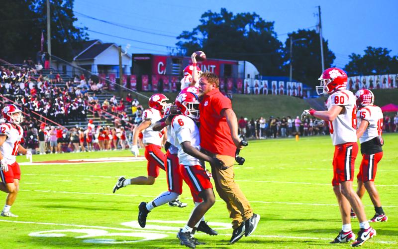 Wesley Branch/The Clayton Tribune.  Rabun County junior linebacker JK Fruster celebrates with assistant coach Ty Maxwell after the Rabun County defense forces a turnover in the Wildcats’ 49-42 road win over Dalton on Sept. 5, 2025.
