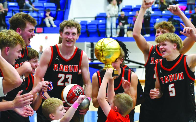 Wesley Branch/The Clayton Tribune. Reeves Page hoists the Battle of the States championship trophy while he and Cal Burrell (left center) celebrate with the Rabun County boys basketball team on Dec. 30 after its 64-59 win over Chesnee. The Wildcats will be at home again on Jan. 13 versus Athens Academy.