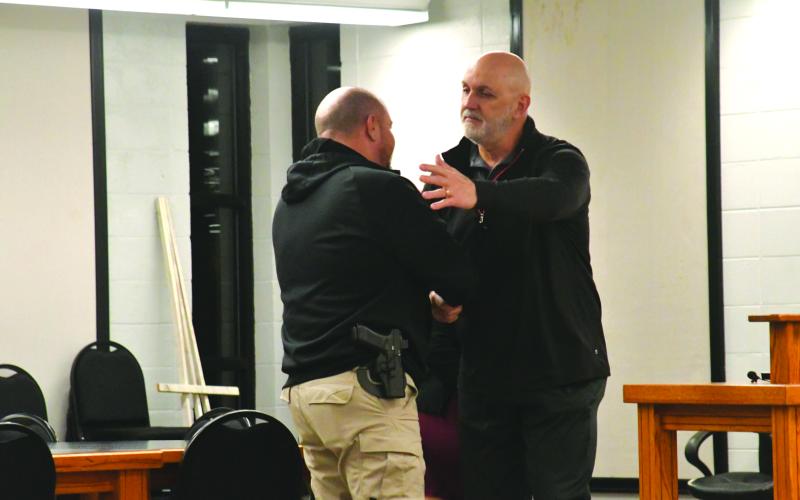 Enoch Autry/The Clayton Tribune. Retiring Clayton Police Chief Andy Strait shakes the hand of new city council member Channing Watts at the conclusion of Tuesday night’s meeting. Colt Woodall (far left) and Mayor Pro Tem Stacy Fountain watch..