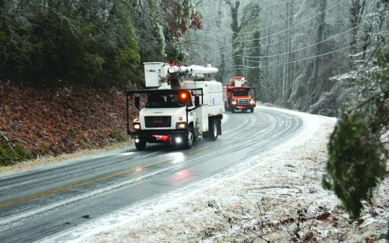 Enoch Autry/The Clayton Tribune. Power trucks drive slowly around a bend on Bridge Creek Road after working on lines near the Rabun County-Habersham County line on Sunday afternoon. Ice on the road refroze that night.
