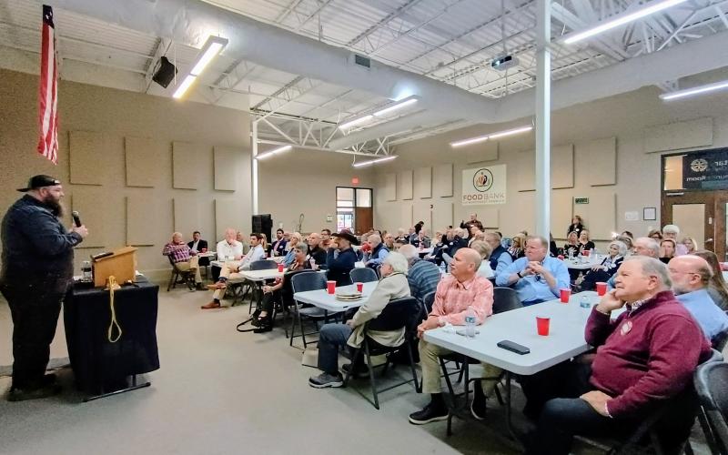 Megan Horn/The Clayton Tribune. Blue Hound Barbecue owner in Dillard Kyle Bryner addresses the Rotary Club of Clayton about his love of cooking during the club meeting.