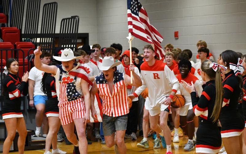 Wesley Branch/The Clayton Tribune. Rabun County senior Reid Giles (right) and sophomore Brock Brady (left) lead Rabun County’s boys basketball team onto the floor ahead of its contest against Banks County on Feb. 10. Coming onto the court dressed in patriotic attire with an American flag, Giles and Brady are RCHS football team members.