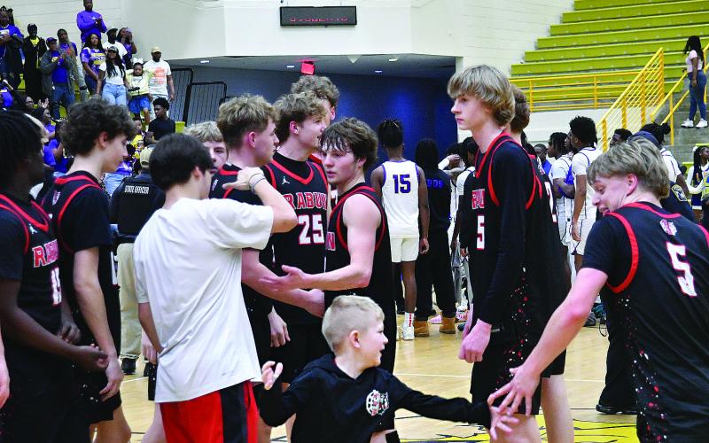 Enoch Autry/The Clayton Tribune. After their 70-59 win against Fitzgerald in the Final Four, junior Landan Bedingfield (5) recieves congratulations from Cal Burrell, brother of RCHS players Cord and Reed Burrell. Rabun County plays for the state championship Friday in the Macon Coliseum against Southwest.
