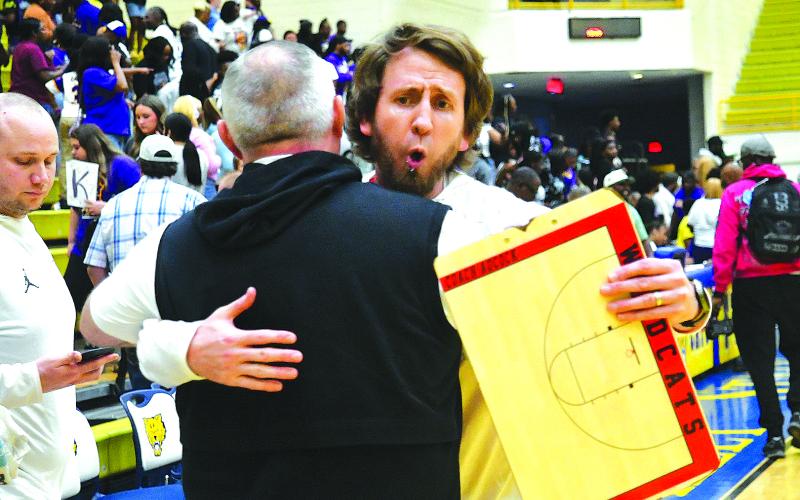 Enoch Autry/The Clayton Tribune. RCHS head coach David Adcock hugs Jonathan Welch, the school’s athletic director, following the Wildcats’ win to advance the title game.