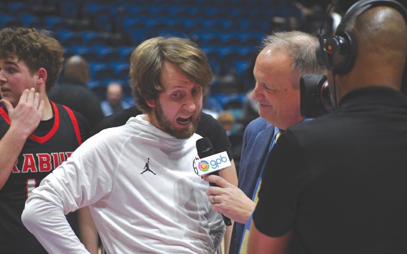 Wesley Branch/The Clayton Tribune. Rabun County head boys basketball coach David Adcock yells “Rabun County, rise up” as he is interviewed by GPB Sports’ Jon Nelson following Rabun County’s 52-43 state championship win over Southwest on March 13.