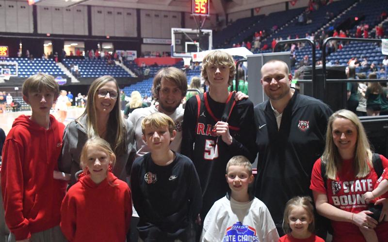 Wesley Branch/The Clayton Tribune. The Adcock family and Page family have become closer this season as Corey Page came on as an assistant coach for head coach David Adcock. April Adcock, David’s wife (second from left in back), said they prayed the right person would come to be the assistant coach and that right person was Corey Page. This photograph of the two families was taken in the Macon Coliseum after the Wildcats won the state title.