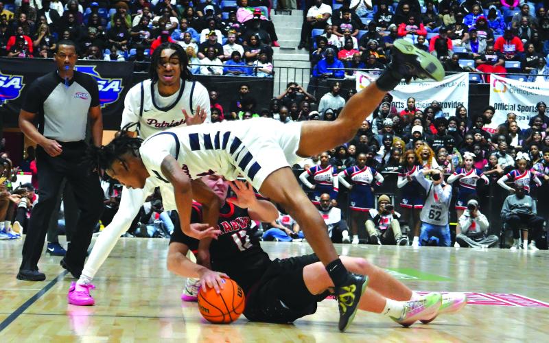 Enoch Autry/The Clayton Tribune. Rabun County’s Reed Burrell goes for a loose ball as Southwest’s senior Montese Green flies over the top of the RCHS junior during the state championship game on March 13 in the Macon Coliseum.