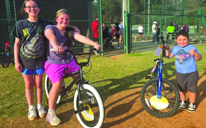 Enoch Autry/The Clayton Tribune. Winners of this year’s bicycles at the April 2 annual Rabun County Recreation Department Easter Egg Hunt are 10-year-old Maleigha Beck (sitting on bike) and Karlos Luka, 4, who is giving a hearty thumbs up. Standing next to Beck is happy friend Anna Frederickson.