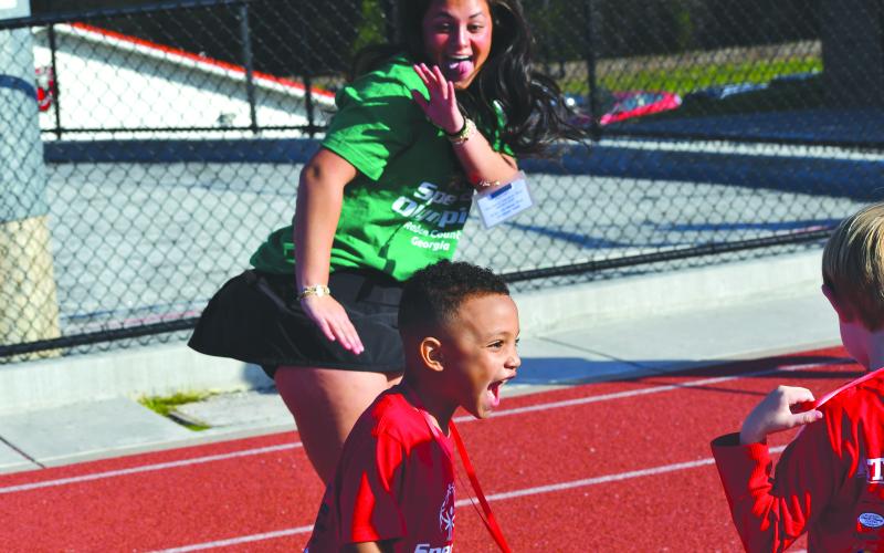 Wesley Branch/The Clayton Tribune. Rabun County Primary School athlete Adrian Appleby cheers and dances with his buddy and Rabun County High School student Ella Weber after competing in the track event at the Rabun County Special Olympics on April 2. Appleby’s dance moves were on display multiple times throughout the afternoon.