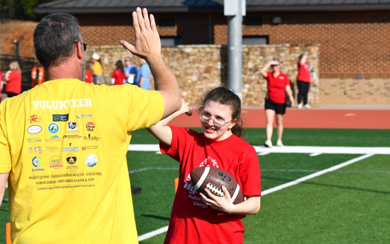 Wesley Branch/The Clayton Tribune. RCHS athlete Ayla Albrecht receives a high-five after hauling in a catch from a volunteer at the football station during the Rabun County Special Olympics on April 2.