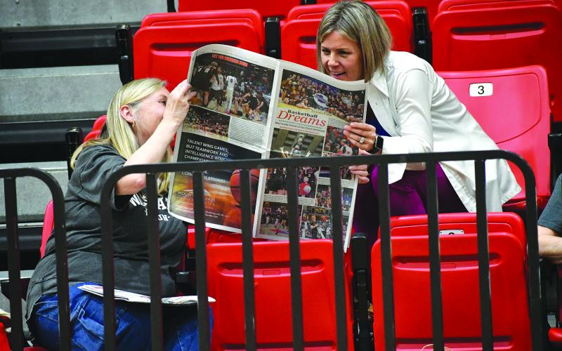 Enoch Autry/The Clayton Tribune. Susan Welch (left), mother-in-law of RCHS head coach David Adcock and grandmother of Trace Adcock shows The Clayton Tribune’s special state title section to Heather Wilson at the March 26 event.