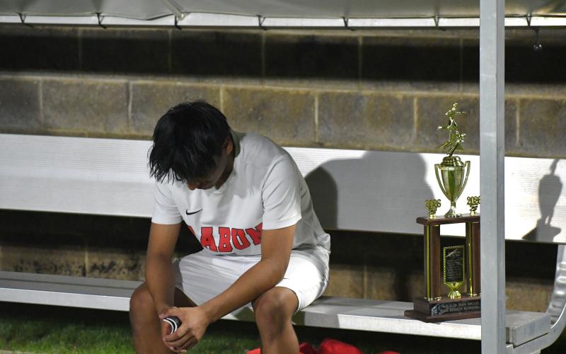Wesley Branch/The Clayton Tribune. Rabun County sophomore Alan Lozada sits on the bench in disbelief after the Wildcats’ loss in PKs to Athens Academy on April 15. Next to Lozada is the region runner-up trophy, which the Wildcats claimed for the second straight year.