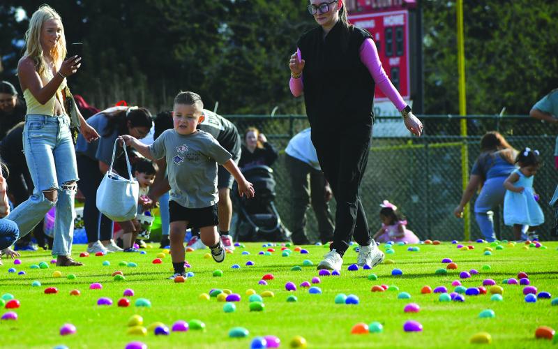 Enoch Autry/The Clayton Tribune. With his mother Della Figueroa (center) watching, 3-year-old Phoenix Figueroa runs with his basket with his name sewn on the side to get eggs at the Rabun County Recreation Department Easter Egg Hunt on April 2.