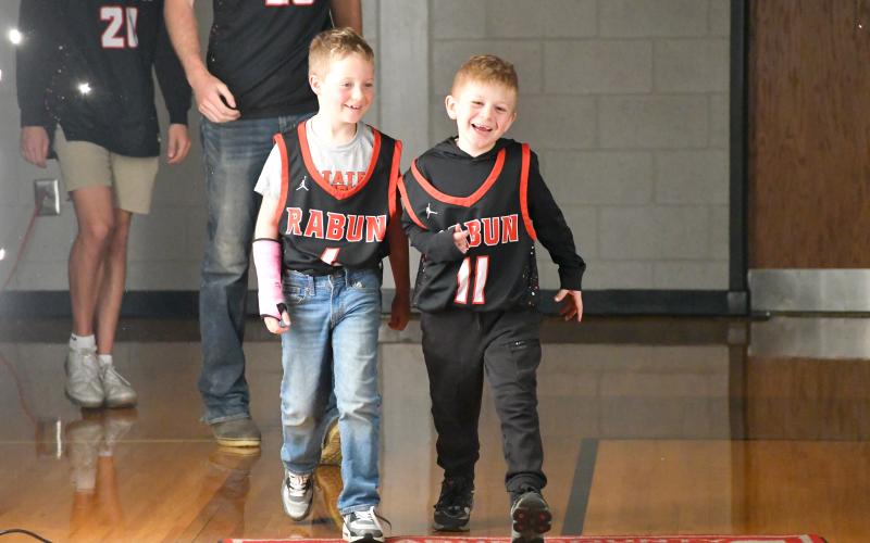 Wesley Branch/The Clayton Tribune. The “goons” Reeves Page (left) and Cal Burrell lead the Rabun County boys basketball team onto the floor for the Wildcats’ state championship celebration at Rabun County High School on March 26. Page, the son of assistant coach Corey Page, and Burrell, the younger brother of players Reed and Cord Burrell, joined the team on the bench throughout the season.