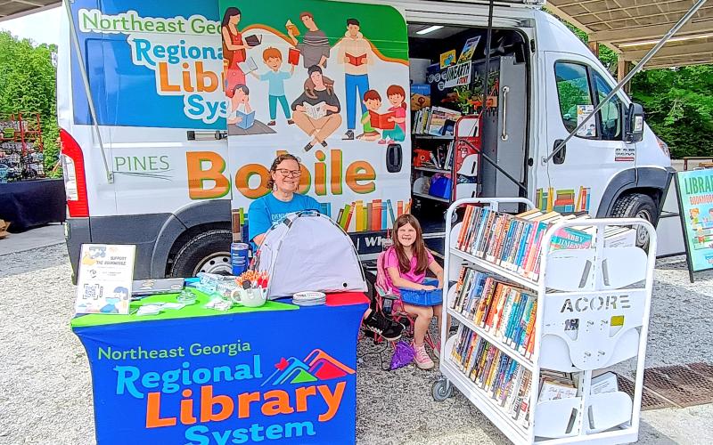 Megan Horn/The Clayton Tribune. Jenny Brooks, outreach and Bookmobile manager, and Gracie Hesse, 8, provide information on the Northeast Georgia Regional Library System and services offered at the Bookmobile.