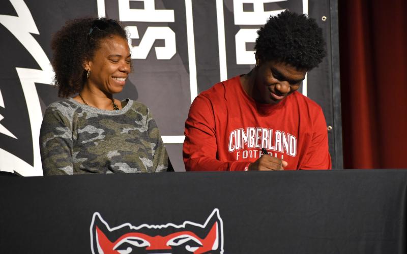 Wesley Branch/The Clayton Tribune. Rabun County senior TJ Hibler signs his letter of intent to Cumberland University while accompanied by his mother on April 30 at the Rabun County High School Fine Arts Building. Hibler, who transferred to RCHS mid-season, was an All-Region selection this season.