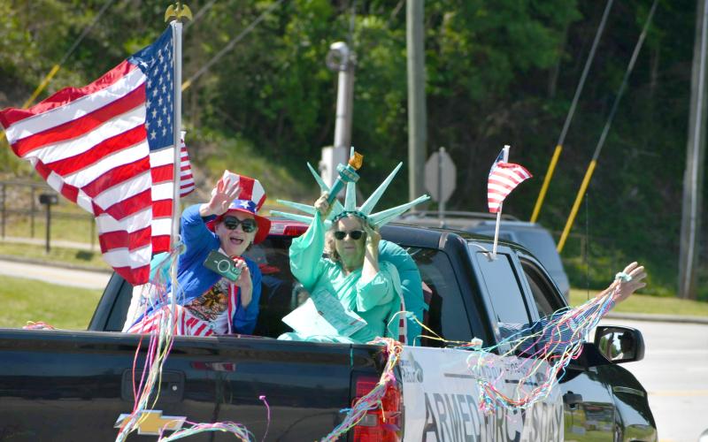 Enoch Autry/The Clayton Tribune. A group of patriotic residents wave American flags at the passing convoy on the Highway 441 sidewalk near the Food Bank of Northeast Georgia.
