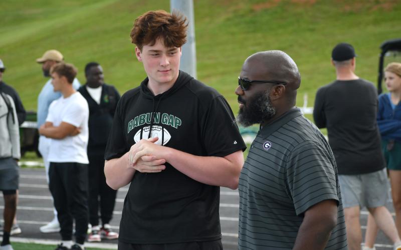 Wesley Branch/The Clayton Tribune. Rabun Gap class of 2027 defensive lineman Marcellus Young Casario talks with Georgia defensive line coach Tray Scott during the Rabun Gap spring college coaches social on Rabun Gap’s campus May 7. Casario has scholarship offers from Georgia, Georgia Tech, Michigan State and others.