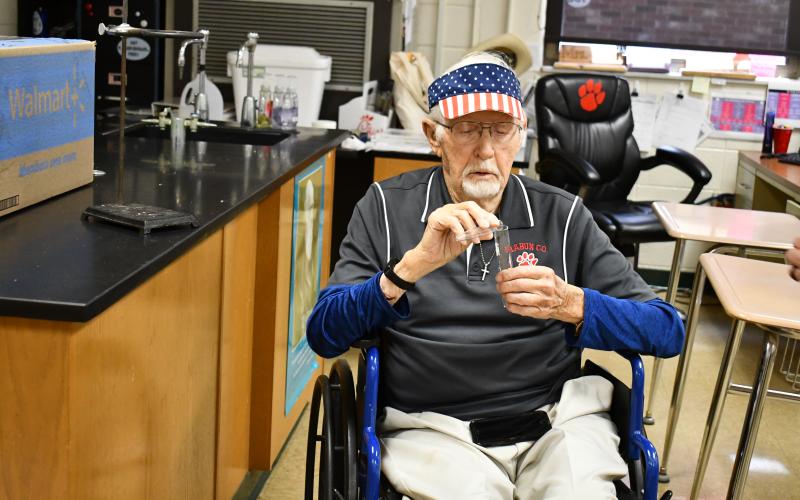 Megan Horn/The Clayton Tribune. Rabun County High School longtime science teacher Clayton Croom, 97, holds beakers in his former classroom at the current high school building. High school students will be in a new building starting this upcoming school year.
