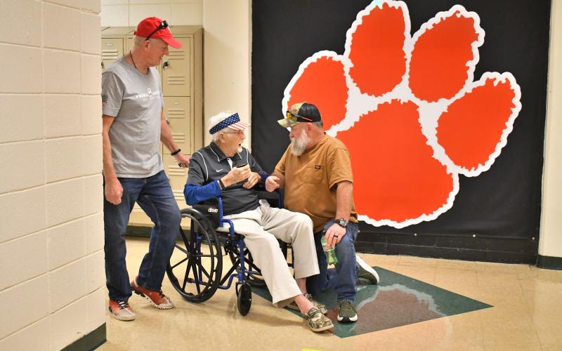 Megan Horn/The Clayton Tribune. Kevin Croom, left, former RCHS science teacher Clayton Croom, 97, and Cary Brown, Class of 1984, converse on the science hallway during the May 16 walkthrough at the high school. Brown was one of Croom’s students.