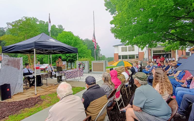 Megan Horn/The Clayton Tribune. Veteran Bruce Gant, left and center under the tent, speaks to a large crowd of community members during the May 25 Memorial Day ceremony held in front of the Rabun County Courthouse. Pictured on either side of Gant are Capt. Chris DiNofrio, U.S. Marine Corps, and Major (Ret.) Doug Wayne, U.S. Army. Gant was this year’s special guest speaker. He was a Navy Corpsman from September 1965 to September 1971. He is a Vietnam Combat veteran and two-time Purple Heart recipient.