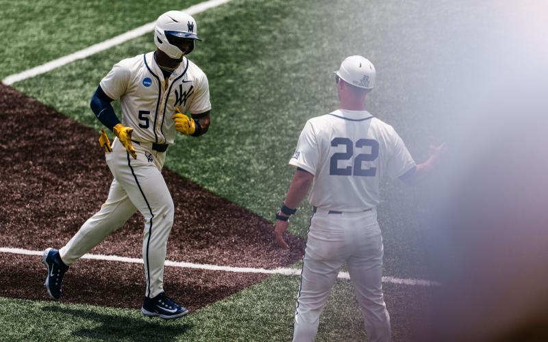 Photos courtesy WVU Athletics. Armani Guzman, who graduated from Rabun Gap, receives congratulations for hitting a home run for the Mountaineers. West Virginia and Troy will face each other in the College World Series. Dylvan Alonso, also a RGNS grad, plays for Troy.
