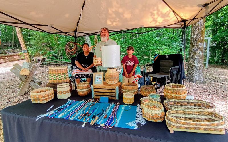 Megan Horn/The Clayton Tribune. Becky Watty and Cleto Montelongo with grandson Aeson Lomas showcase these beautiful handmade baskets featuring Cherokee designs during Heritage Days at Foxfire Friday, June 5, and Saturday, June 6.
