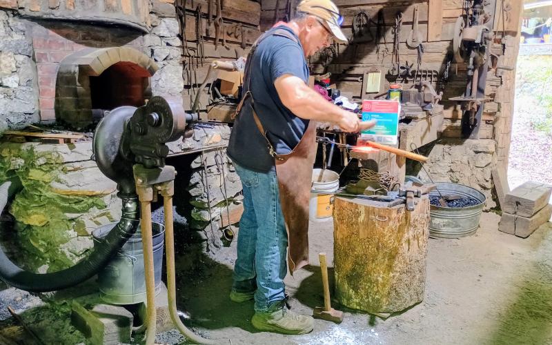 Megan Horn/The Clayton Tribune. Wind Chapman, assisted by Kerstin Flannery, demonstrates Blacksmithing in his Blacksmith Shop during Foxfire Heritage Days which was held Friday, June 5, and Saturday, June 6.