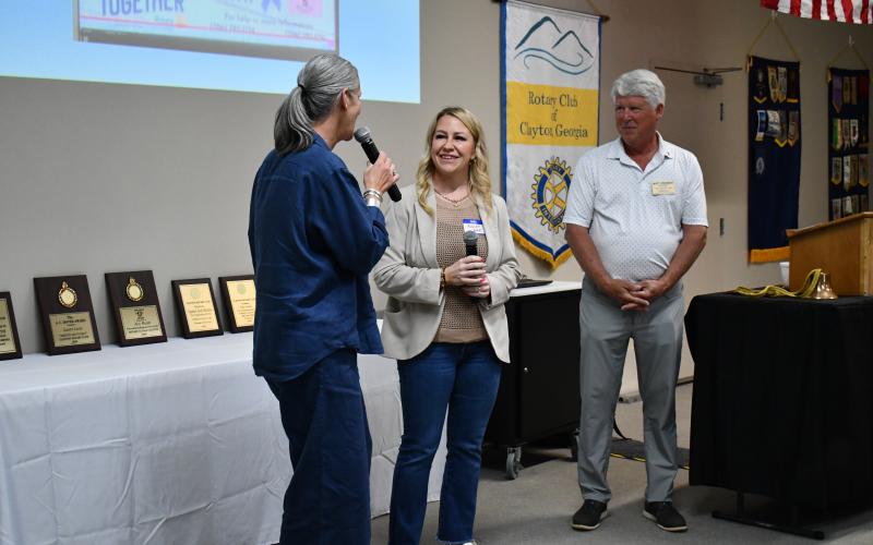 Megan Horn/The Clayton Tribune. Caroline Wallis, executive director of Fight Abuse In The Home (F.A.I.T.H.), left, gives words of encouragement to Women of Worth (WOW) Recovery Director Ashley York, as the duo accepts The Wheel Award from the Rotary Club of Clayton for the partnership between F.A.I.T.H. and WOW during Rotary’s Thursday, June 4, lunch meeting. Rotary Club of Clayton President Matt Freeman congratulates the pair.