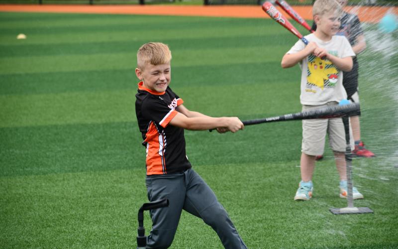 Wesley Branch/The Clayton Tribune. Campers practiced their swing on water-ballon like balls that exploded with water upon contact. One of the RCHS campers follows through on his swing after making contact.
