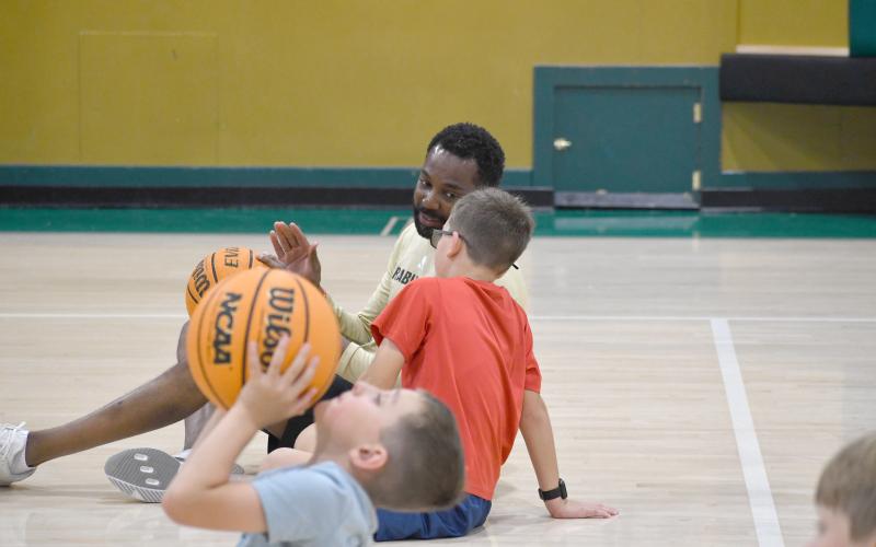 Wesley Branch/The Clayton Tribune. T: Rabun Gap assistant boys basketball coach Darrick Cureton helps camper Thomas Kaczmarski (red shirt) with his shooting form during a drill at Rabun Gap’s kids basketball camp.