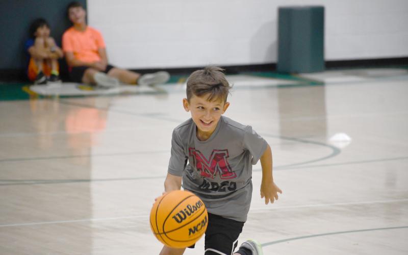 Wesley Branch/The Clayton Tribune. Rabun Gap kids basketball camper Kingston Johnson smiles as he races down the floor during Rabun Gap’s kids camp.