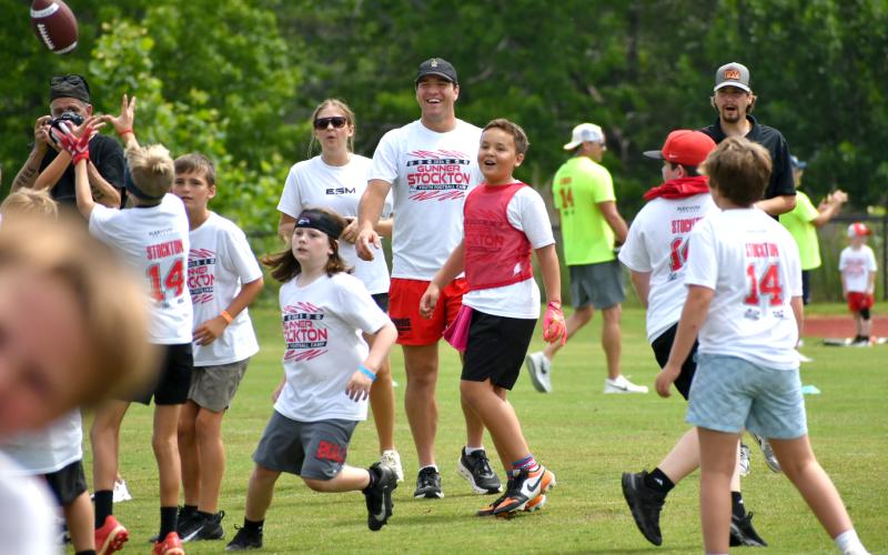 Enoch Autry/The Clayton Tribune.  Gunner Stockton smiles while watching the campers stretch to pull in a pass from the Georgia starting quarterback during second annual event in Hall County.
