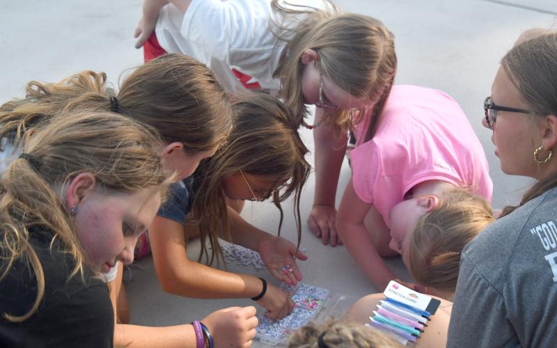 Wesley Branch/The Clayton Tribune. Campers make their bracelets with their word of encouragement at the Rabun County softball camp at Rabun County High School on June 15. The words the campers picked will go on a long strand that the high school varsity team will take with them to games this season.