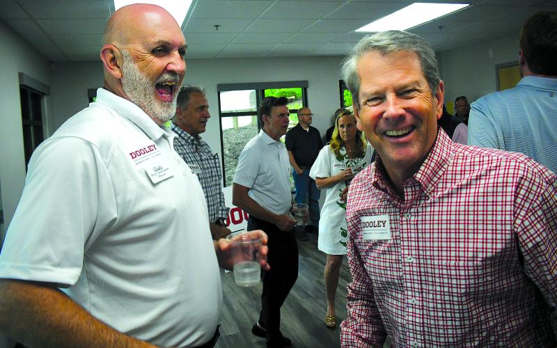 Enoch Autry/The Clayton Tribune. Clayton Mayor Roy Quilliams shares a laugh with Gov. Brian Kemp after the governor puts a Dooley for U.S. Senate sticker on Quilliams’ shirt at the May 29 Meet &amp; Greet in Rabun County.