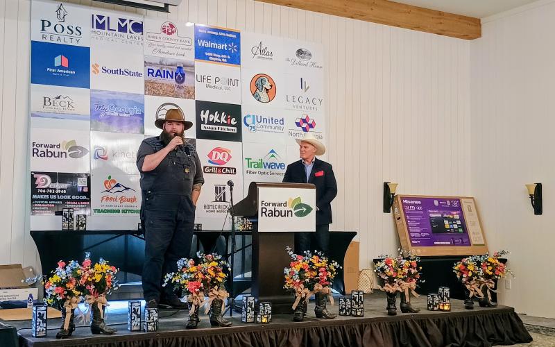 Megan Horn/The Clayton Tribune. Kyle Bryner, owner of Blue Hound Barbecue, thanks membership and community members for their support and for the honor of receiving the Kathy Blalock Award. Pictured right is Forward Rabun President Rick Story.