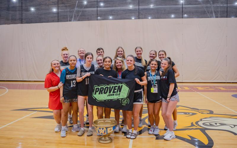Image via DeeDee Dillard. The Rabun County High School girls basketball team poses with the FCA Camp championship cup at Emmanuel University.