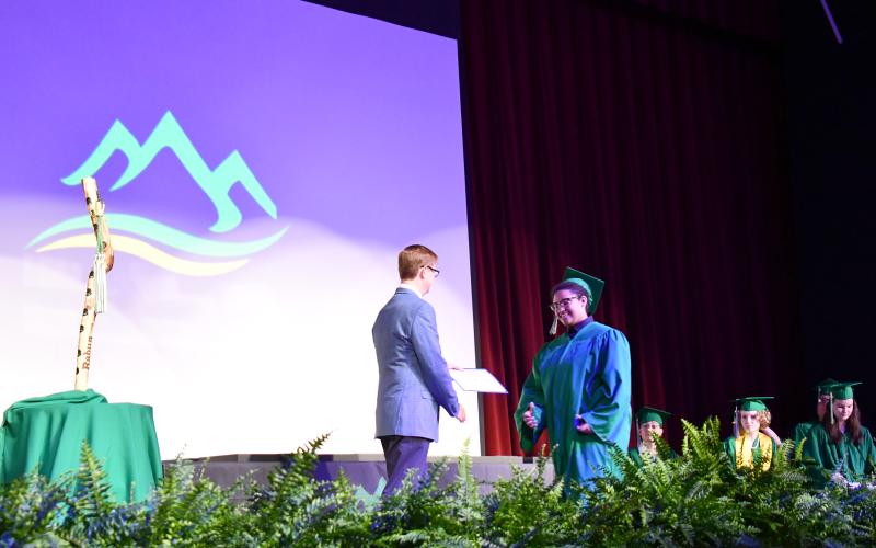 Megan Horn/The Clayton Tribune. Rabun Mountain Education Campus Principal Allen Blair, left, happily hands a high school diploma to an excited Emerald Vaylin Pittman. Rabun Mountain Education held a graduation ceremony for the Class of 2026 on Saturday, May 23.