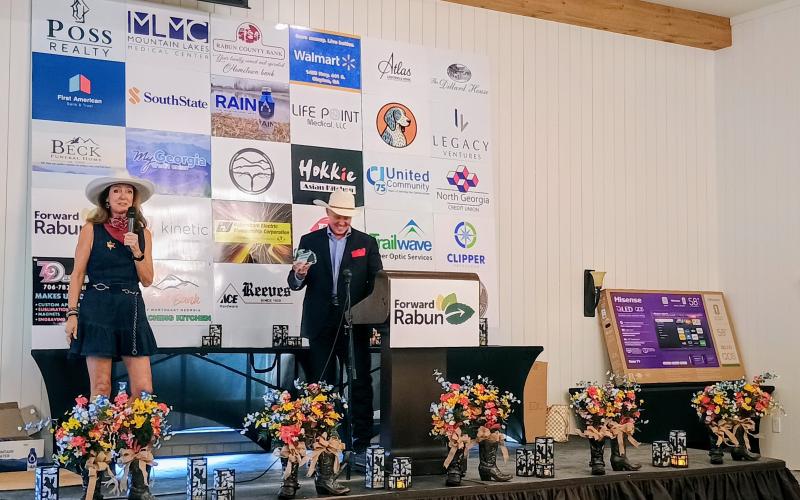 Megan Horn/The Clayton Tribune. Brenda Patterson, owner of White Birch Inn, White Birch Provisions and The Watchmaker’s Workspace, received the 2026 Entrepreneur of the Year award. Patterson thanked the community for their support. She stands on stage with Forward Rabun President Rick Story.