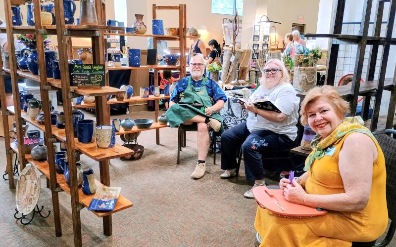Megan Horn/The Clayton Tribune. Evan and Pamela Kohler-Camp, left, and Marissa Trudel are all smiles at the North Georgia Arts Guild’s Painted Fern Art Festival last weekend. The Kohler-Camps featured pottery from “And Sarah Laughed Pottery Studio.”