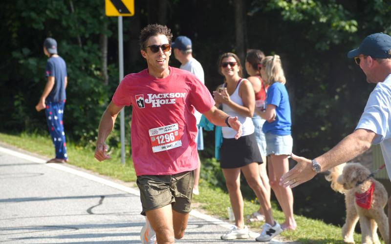 Wesley Branch/The Clayton Tribune. Jeffery Shelley, the overall winner and male winner of the 42nd Lake Burton Fun Run, receives a high-five as he approaches the finish line. Shelley, who is from Auburn, Ala., finished the two-mile run with a time of 11:32.