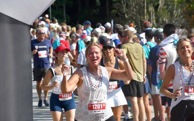 Wesley Branch/The Clayton Tribune. Carol McPherson of Dahlonega, Ga., celebrates as she crosses the finish line of the 42nd Lake Burton Fun Run on July 4 at LaPrade’s Marina. McPherson, 69, finished the two-mile run with a time of 29:08.
