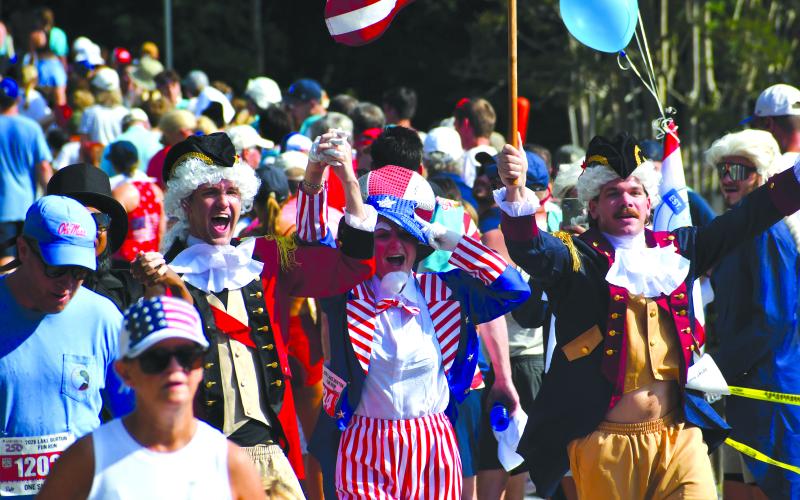 Wesley Branch/The Clayton Tribune. Several participants of the Lake Burton Fun Run showed their patriotism by wearing red, white and blue, or by dressing up in costumes like the trio celebrating here as they cross the finish line. Despite the warm temperatures, thousands were in attendance on July 4 for the 42nd annual Lake Burton Fun Run from Moccasin Creek State Park to LaPrade’s Marina.