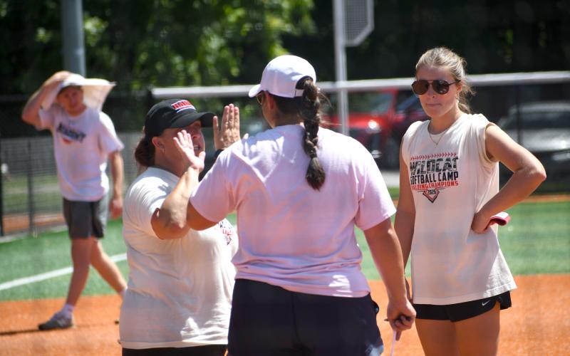 Wesley Branch/The Clayton Tribune. Rabun County High School head softball coach Jessica Evans (left) and Habersham Central head softball coach Karly Thompson (middle) high five after the teams finished their summer scrimmage on July 20 at Rabun County High School. Evans and the Lady Cats will open the season on Aug. 3 at home versus East Jackson.