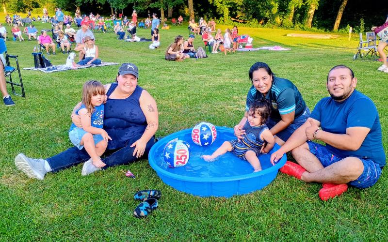 Megan Horn/The Clayton Tribune.  Marie and 2-year-old Toulouse, left, attend the City of Clayton’s inaugural drone show event July 1. Pictured right is the family of Hugo Juarez, Nathaniel Juarez, 2, and Alma Lopez. There were many kids’ activities to choose from.