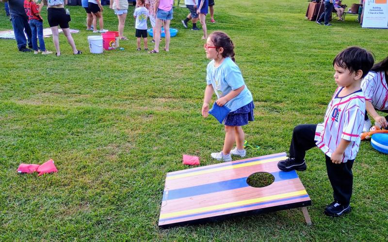 Megan Horn/The Clayton Tribune. Nova Gonzalez, 6, and Sabastian Castillo, 4, play cornhole as one of the many kids’ games during the July 1 event at Clayton City Hall.