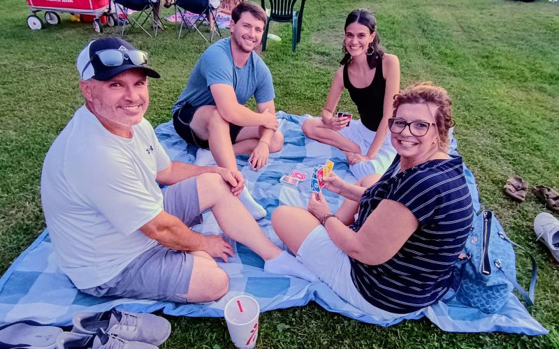 Megan Horn/The Clayton Tribune. Randall Dean, left; Dawson Dean; Abbey Ortiz; and Laurie Dean play UNO! As they wait for the start of the inaugural drone show in Clayton July 1.